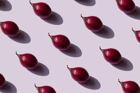 Red onions pattern on a light purple background. Sweet onions for salads.の写真素材