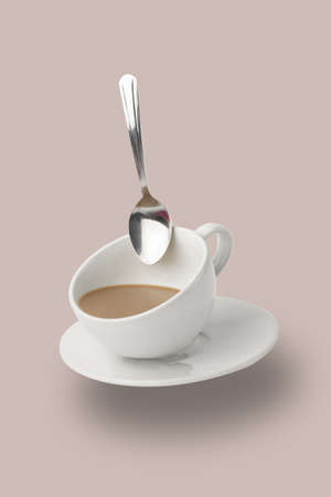 Levitation of Cup of Coffee with a spoon. White mug flying on the air on pastel beige background. Minimal conceptの写真素材