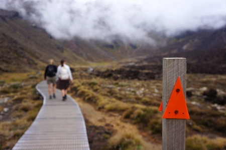 Two women walking on a trail that is gonna take them over the Tongariro crossing in New Zealand. A trek taking them over 19.4 kilometres of stunning scenery consisting of the three mountain peaks of Tongariro, Ruapehu and Ngauruhoe (also known as Mount Doのeditorial素材