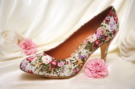 High heeled shoe surrounded by light pink flowers and white velvet. A romantic setting that screams WEDDING.の写真素材