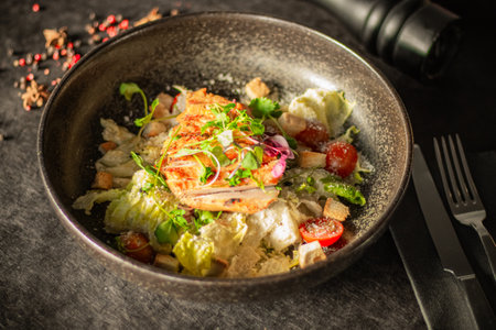 A salad with grilled chicken, cherry tomatoes, croutons, lettuce, and microgreensの写真素材