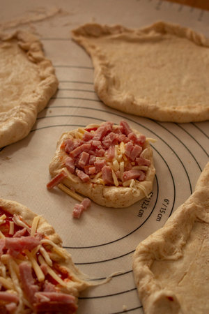 A close-up of raw pizza dough being shaped and topped with shredded cheeseの写真素材