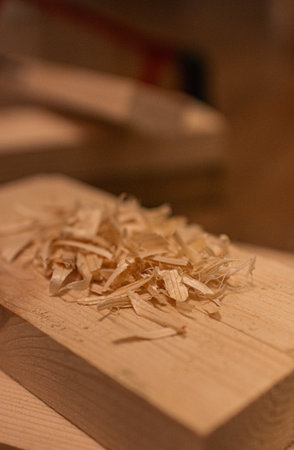 A pile of wood shavings rests on a wooden plankの写真素材