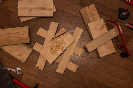 Wooden planks, shavings, a red-handled saw, a wrench, and a tape measureの写真素材