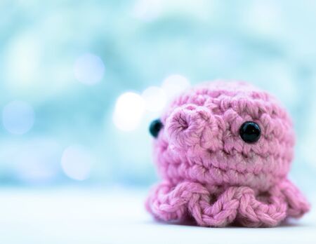 Cute pink crochet squid (or octopus) with blue backgroundの写真素材