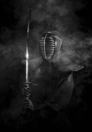 Kendo samurai in armor standing in the smoke with shining sword