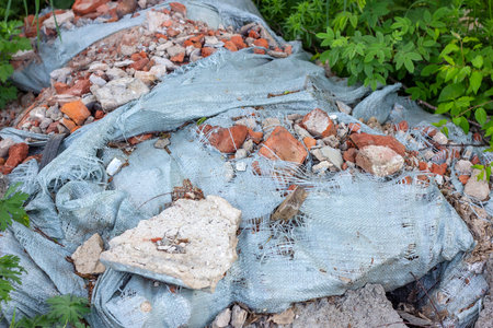 Ð¡onstruction garbage, debris and waste rubble in a remote green area. Nature and soil pollution...