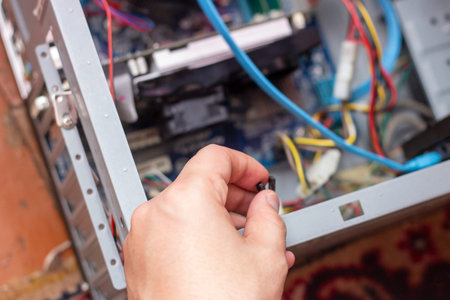 The young technician hold the cord for repairing the computer in his hand. Computer hardware,...