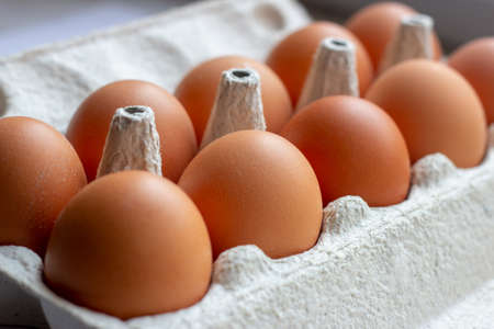 Stack of many brown and speckled fresh raw chicken eggs in the cardboard tray box packaging for sale in supermarket.の写真素材