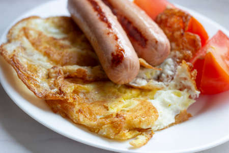 Traditional breakfast set with eggs, sausages and fresh tomatoes on rustic white wooden table. Food concept.の写真素材