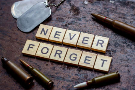 The words never forget with bullets  and old and worn military dog tags on rusty metal background.の写真素材