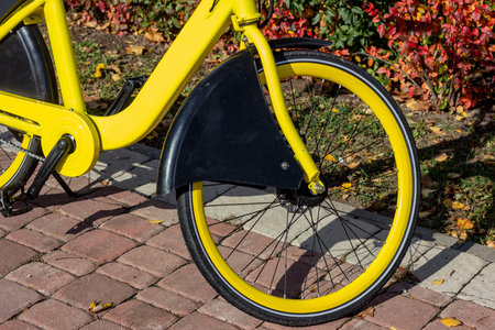 Bright yellow bicycle wheel standing  in the city street in autumn season.の写真素材