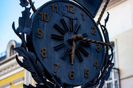 Big black retro metal clock on the modern city street background.の写真素材