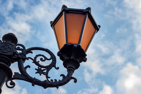 Old vintage city street lantern on blue cloudy sky background in the public place.の写真素材