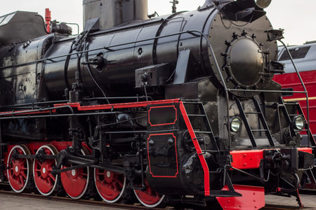 Old black and red retro steam locomotive at the railway station. Vintage train staying on the...