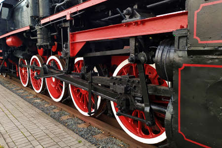 Old black and red retro steam locomotive wheels at the railway station. Vintage train staying on the railroad.の写真素材