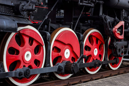 Old black and red retro steam locomotive wheels at the railway station. Vintage train staying on the...