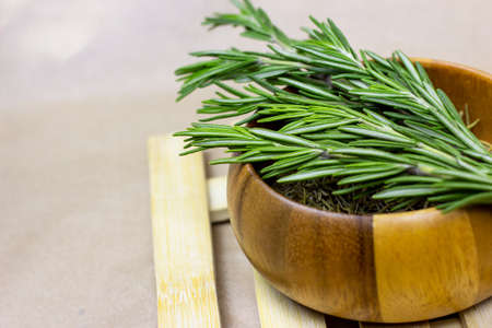 Bright fresh green and dried rosemary branches, twigs and leaves in a wooden bowl and board on light background.の写真素材