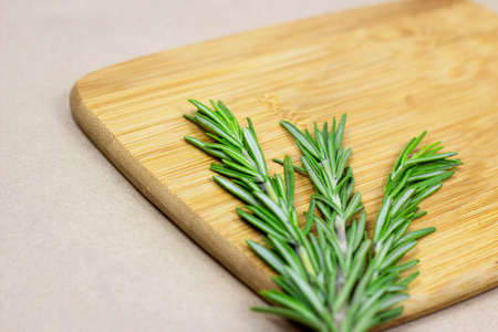 Bright fresh green rosemary branches, twigs and leaves on a wooden board on light background.の写真素材