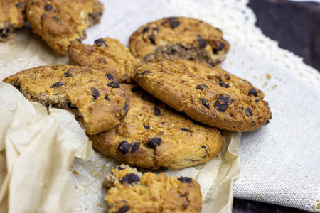 Freshly baked American chocolate chip cookies on rustic black metal table background.