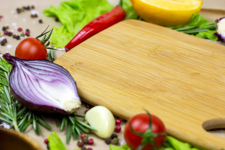 Brown wooden cutting board with summer vegetables and champignon mushroom on table background.