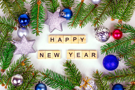 Happy New Year text sign and Christmas decoration with green fir tree branches and blue and silver...