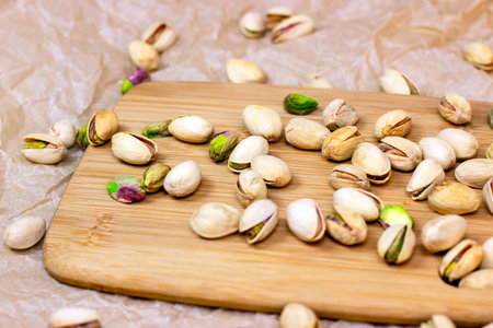Roasted salted pistachio nuts in nutshell on wooden board background.