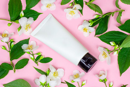 White plastic cosmetic container for moisturizing cream as a mock up with bright fresh jasmine...