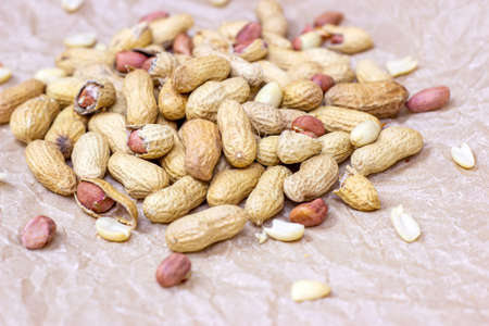 Raw unpeeled peanut nuts in nutshell on light paper background.の写真素材