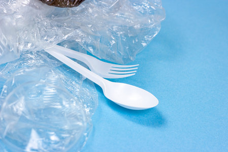 Plastic spoons, forks and cups as a disposable waste with copy space on bright blue background. Environmental pollution and litter recycling concept.の写真素材