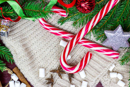 Top view of bright Christmas and New Year celebration background with fir tree branches, holiday decorations and sweet red striped lollipops on light rustic backdrop with copy space.の写真素材