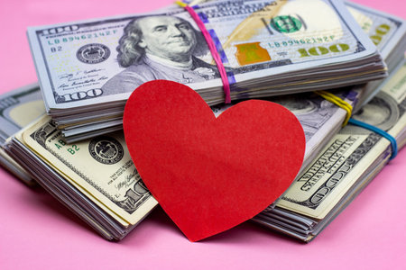 Dollar packs and big red paper heart on money background. Sex, love and prostitution concept.