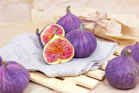 Fresh organic purple fig fruit on the wooden board background in the kitchen.
