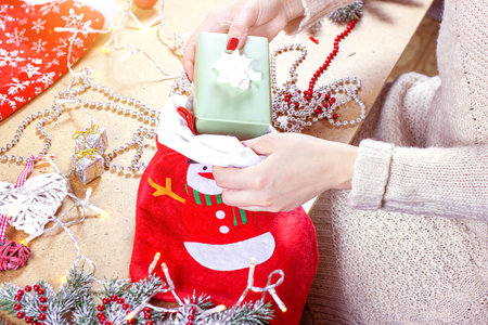 Woman hands holding a gift box on Christmas and New Year decorations background. Xmas presents and...