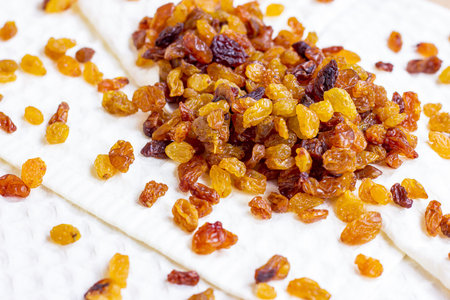 Brown raisins (dried yellow grape) on light textile background.の写真素材