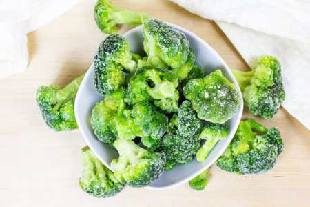 Top view of fresh green frozen broccoli in small white bowl on light background.の写真素材