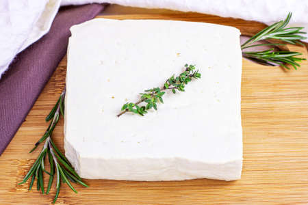 Raw organic vegetarian tofu with fresh rosemary on wooden background.の写真素材