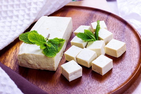 Raw organic vegetarian tofu slices with fresh mint on wooden background.の写真素材
