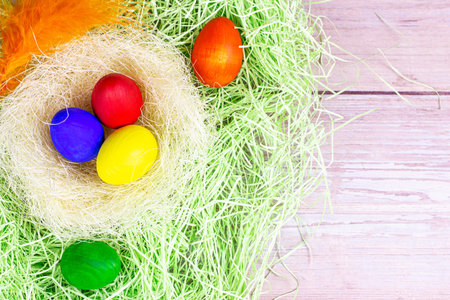 Top view flat lay colorful painted Easter eggs decorations in the nest with copy space on light...