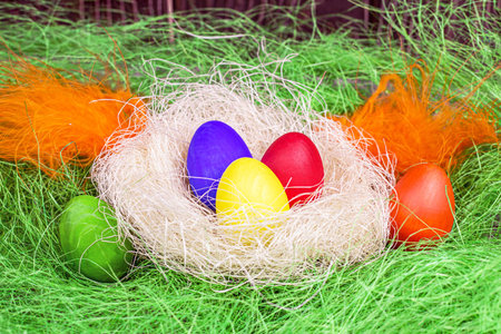 Colorful painted Easter eggs decorations in the nest on light green background.