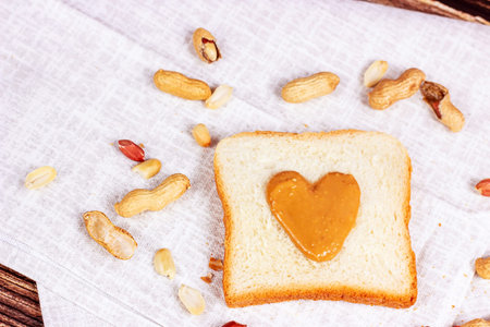 Homemade toasts for breakfast with fresh crunchy heart shaped peanut butter and nuts on light...