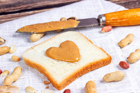 Homemade toasts for breakfast with fresh crunchy heart shaped peanut butter and nuts on light...