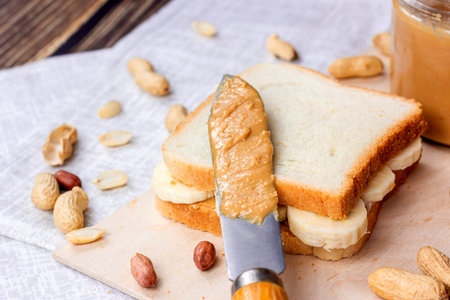 Homemade sandwich for breakfast with fresh crunchy peanut butter and bananas on light textile...