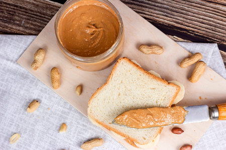 Top view of homemade sandwich for breakfast with fresh crunchy peanut butter and bananas on light...