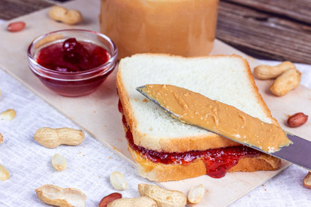 Homemade sandwich for breakfast with fresh crunchy peanut butter and strawberry jelly on light background.の写真素材