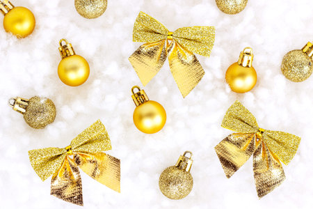 Bright golden and yellow Christmas decorations (ribbons, baubles, ornaments) flat lay on white...