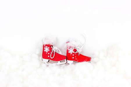 Bright red vintage toy skating shoes on white artificial snow background with copy space. Winter sports, Christmas and New Year holiday design concept.の写真素材