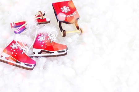 Bright red vintage toy skating shoes, ski, sleigh on white artificial snow background with copy space. Winter sports, Christmas and New Year holiday celebration concept.の写真素材