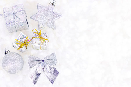 Bright silver Xmas decorations (ribbons, baubles, ornament) flat lay on white artificial snow background with copy space. Christmas and New Year traditional holiday celebration concept.の写真素材