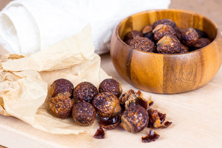 Brown dry soap nuts (Soapberries, Sapindus Mukorossi) in a wooden bowl for organic laundry and...